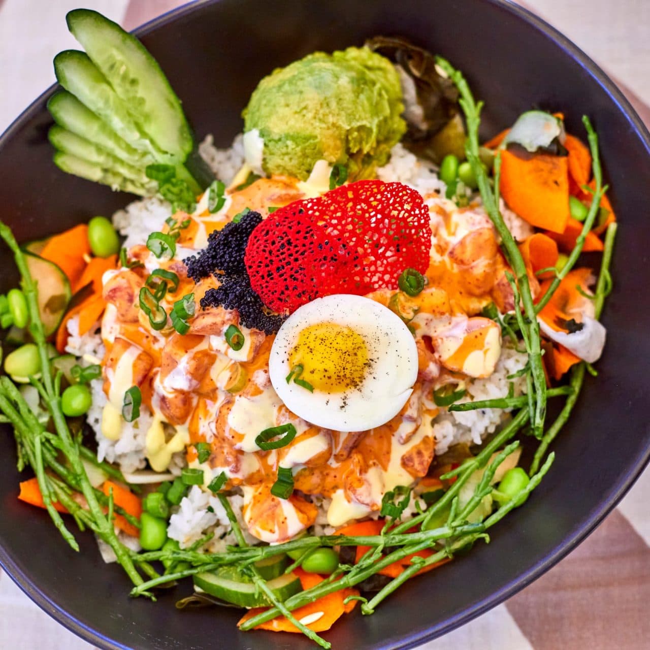 A close-up of Tiki's Grill & Bar's Ahi Royale poke bowl, showing each ingredient, including fresh ahi, avocado, and Kahuku sea asparagus.