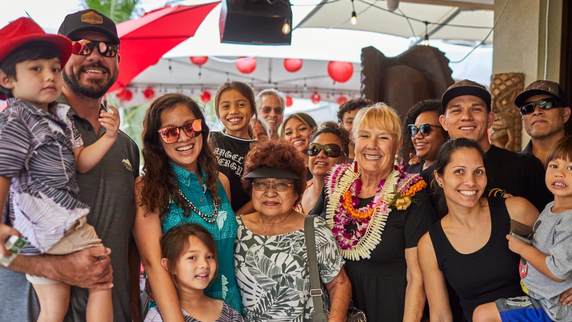 A large local family celebrating a birthday at Tiki's Grill & Bar with live music, showcasing a multi-generational ohana gathering.